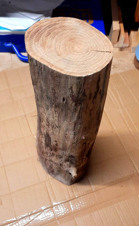 A thick, curved wooden elm log with a flat, circular top. It appears to be a section of a tree trunk.