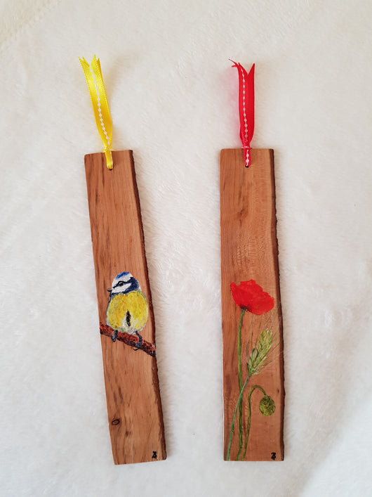 Two wooden bookmarks, one with a hand-painted blue tit and the other with a red poppy. Both bookmarks are tied with ribbons.